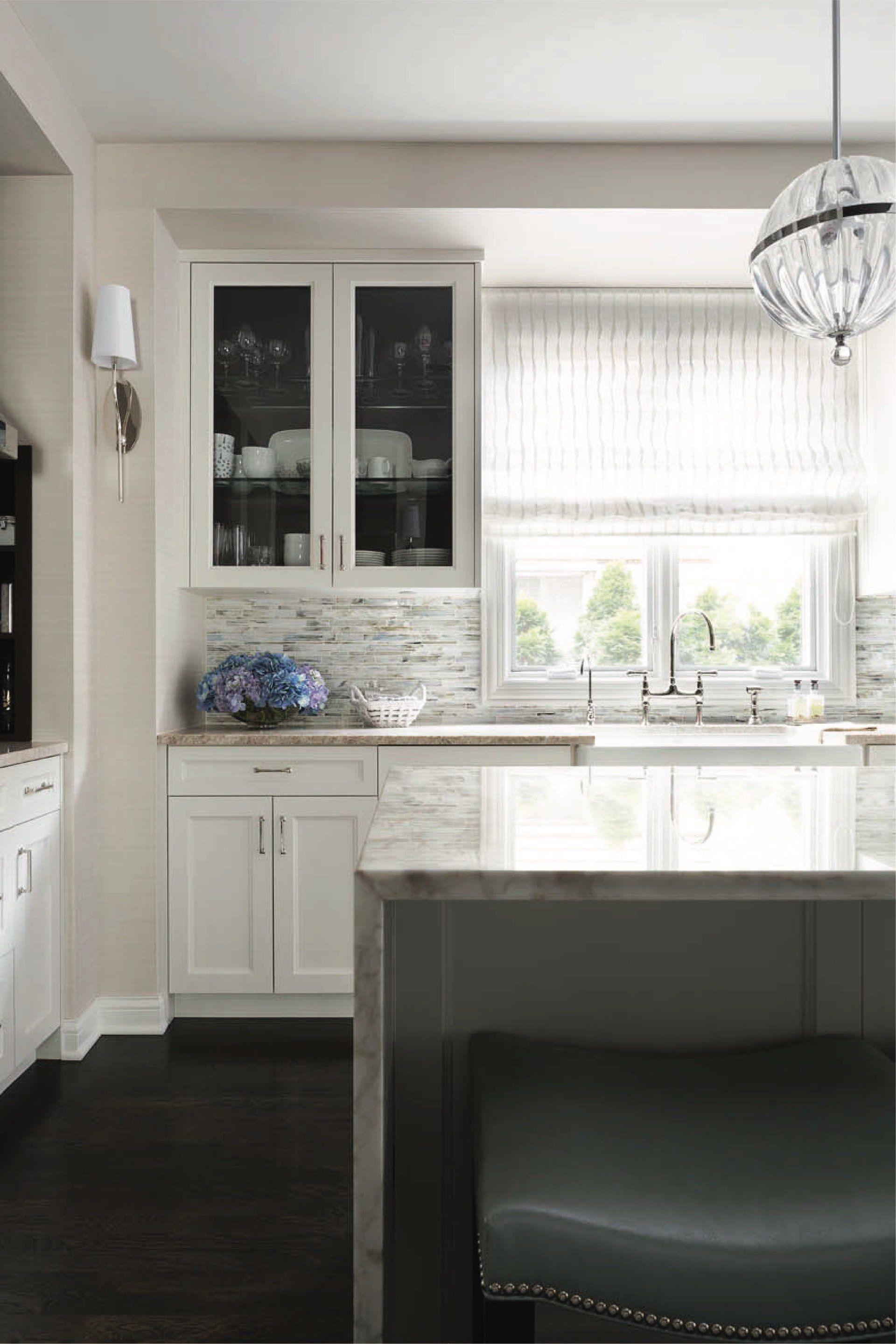 A kitchen with white cabinets , a sink , and a large island.